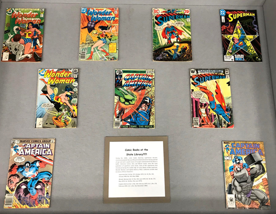 Display case with Superman, Captain America and Wonder Woman comics