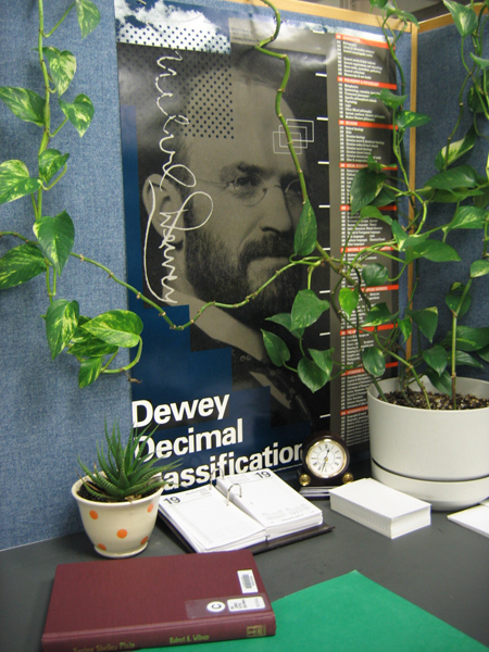 palnts in front of a poster of Melvil Dewey and the Dewey Decimal Classifications