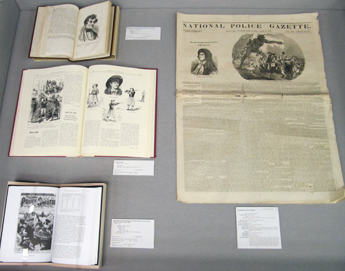 Display Case 1, with one issue of the National Police Gazette and three books, open to show various illustrations, about the newspaper.