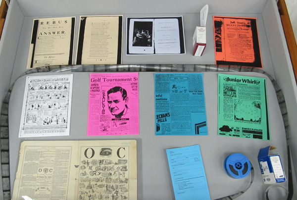 Display case 1, showing examples of rebuses and a roll of microfilm.