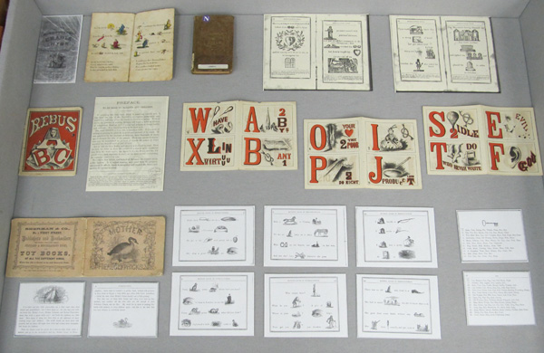 Display case 3, showing additional examples of rebuses, including pages from an alphabet book and a Mother Goose book.