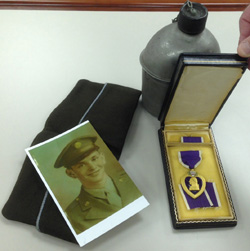 Photo of Bernie Staller and artifacts from his military service, including a Purple Heart medal.